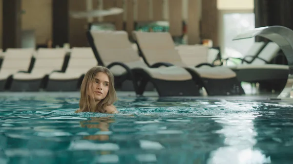 Hermosa mujer nadando en una piscina de lujo. Chica joven abajo de las escaleras piscina — Foto de Stock