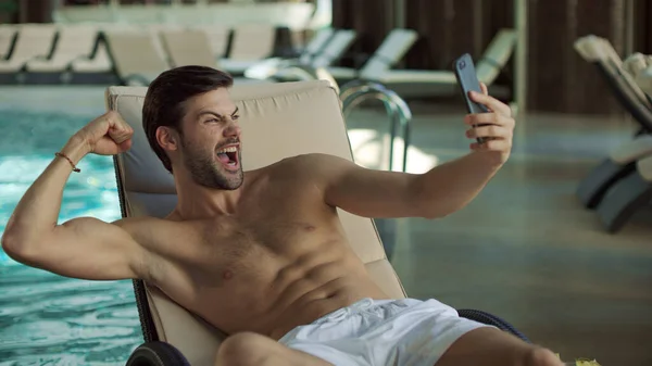 Primer plano hombre divirtiéndose cerca de piscina cubierta. Hombre haciendo selfie en el teléfono móvil —  Fotos de Stock