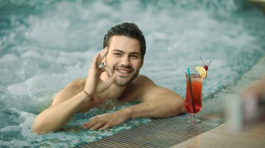 Gülümseyen adamın makro hareketi. Lüks havuzda kameraya poz veren adam..