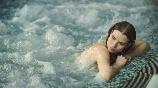 Porträtt av sexig kvinna som kopplar av i poolen inomhus. Söt flicka njuter jacuzzi spa — Stockfoto