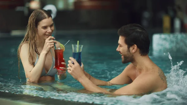 Primer plano de una joven pareja descansando en la piscina. Feliz hombre y mujer bebiendo cócteles —  Fotos de Stock