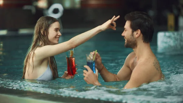 Primer plano sexy pareja relajante en el spa de la piscina. Feliz hombre y mujer disfrutando de bebidas —  Fotos de Stock