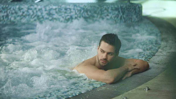 Man relaxing in spa on vacation. Male resting in jacuzzi at wellness center — Stock Photo, Image