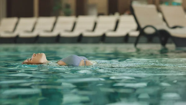 Nahaufnahme junge Frau beim Schwimmen im Pool. Hübsches Mädchen beim Baden im Wellness-Center — Stockfoto