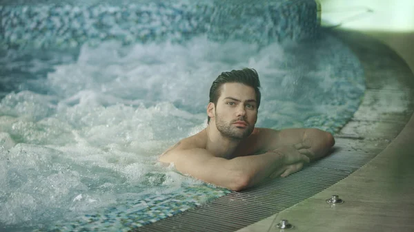 Jakuzide dinlenen yakışıklı adam. Girdap banyosunda dinlenen seksi adam.