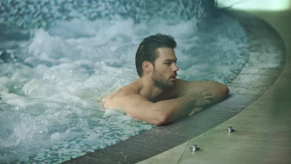 Jakuzide dinlenen yakışıklı adam. Çekici adam girdap banyosunda dinleniyor.