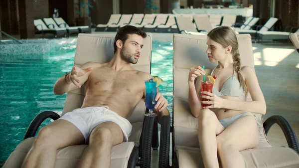 Närstående par dricker cocktails i solstolen. Man och kvinna flörtar tillsammans — Stockfoto
