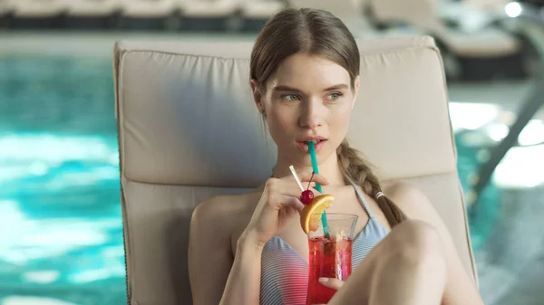 Porträt einer jungen Frau, die am Pool einen Cocktail trinkt. Frau flirtet in Liege. — Stockfoto