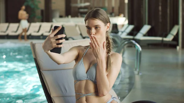 Porträt einer hübschen Frau, die ein Selfie in der Nähe eines Swimmingpools macht. Mädchen schickt Luftkuss — Stockfoto