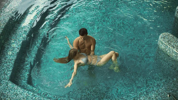Paar mit Blick auf den Pool im Wellnesshotel. Paar ruht sich im Pool im Wellnessbereich aus — Stockfoto