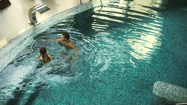 Obere Ansicht des glücklichen Paares, das im Pool schwimmt. Schönes Paar entspannt sich im Pool — Stockfoto