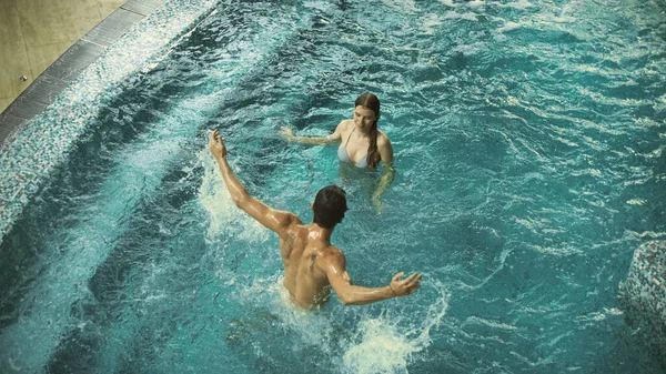 Vista dall'alto della coppia felice che si diverte in piscina. Sorridente coppia spruzzi in piscina — Foto Stock