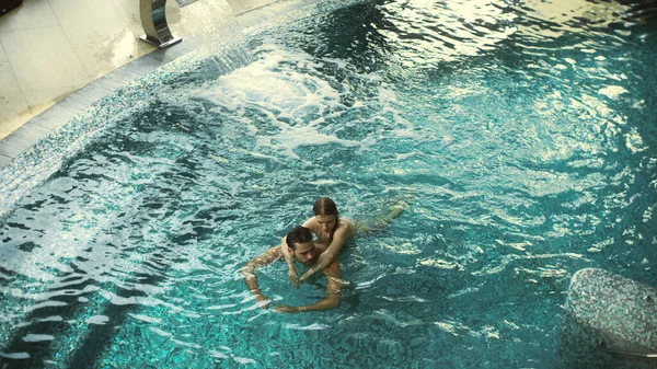 Draufsicht auf entspanntes Paar, das sich im Pool umarmt. Glückliche Männer und Frauen entspannen sich im Wasser — Stockfoto