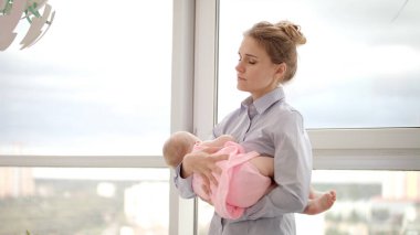 Anne, bebeği pencerenin yanında tutmaktan yoruldu. İş annesi bebek taşıyor.