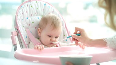 Bebek püre yemiyor. Anne kızını besliyor. Bebek akşam yemeği yiyor.