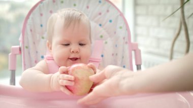 Bebek koltuğunda elma yiyen güzel bir bebek. Tatlı çocuk meyve tadıyor.