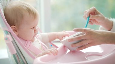 Üzgün bebek lapa yemek istemiyor. Koltuktaki küçük bebek yemek yemiyor.