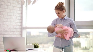 Ofiste annenin kucağında bebek var. Anne kucağında uyuyan bebek.