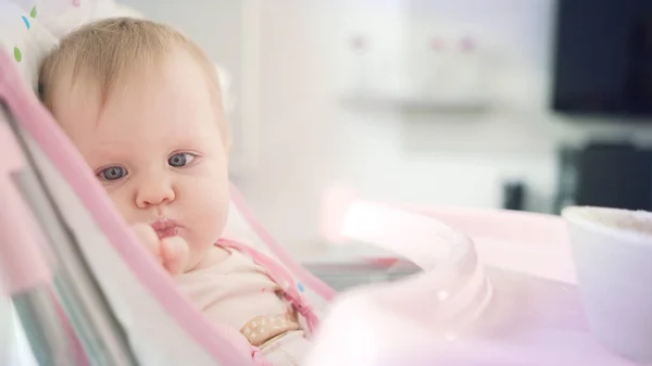 Baby isst mit Löffel. Nettes Kind schmeckt Brei. Kleinkind isst im Babystuhl — Stockfoto