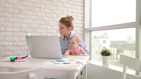 Businesswoman with kid working with documents. Freelancer at maternity leave