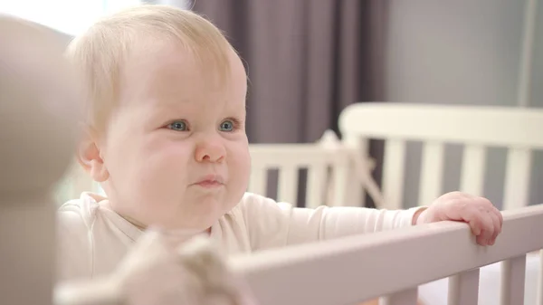 Trauriges Baby im Bett stehend. Wenig Babygefühle. Kleinkind lernt, im Bett zu stehen — Stockfoto