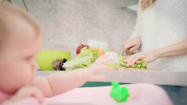 Annem bebek için yemek yapıyor. Annem yeşil salata kesiyor. Sağlıklı yemek pişiren kadın