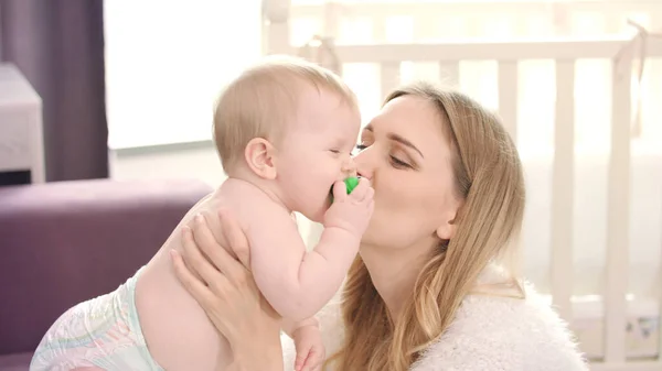 Gelukkige moeder die baby kust. Jonge moeder knuffelen baby — Stockfoto