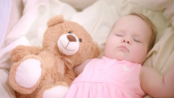 Mädchen schläft mit Spielzeug im Kinderbett. Süße Schlafenszeit. Kleines Mädchen träumt im Bett — Stockfoto