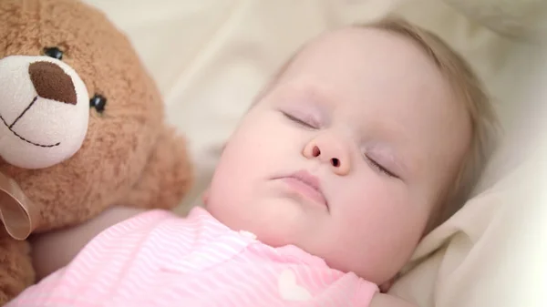 Liebenswertes Baby, das im Bett schläft. Porträt eines schlafenden Babys mit Spielzeugbär — Stockfoto