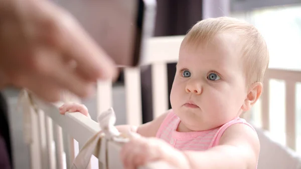Schöner Säugling beim Handy gucken. Baby sucht Smartphone im Kinderbett — Stockfoto