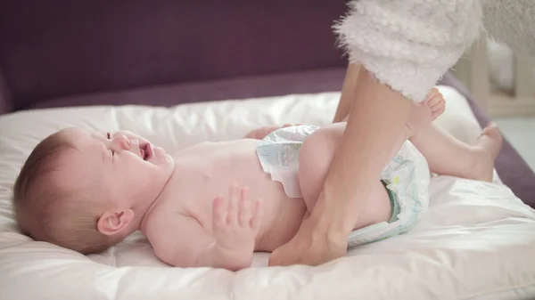 Mamãe se importa chorando bebê. O bebé chora de fraldas. Choro infantil no guardanapo branco — Fotografia de Stock