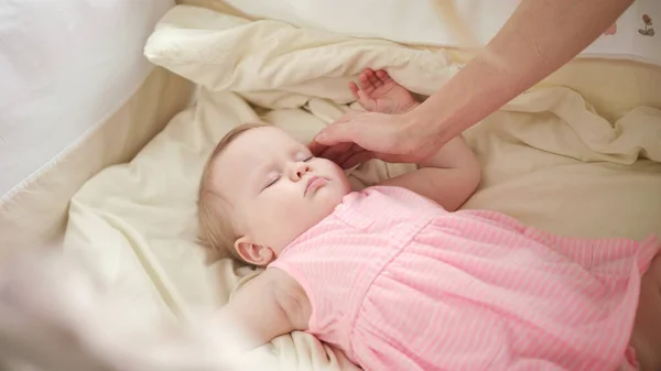 Mooie baby slaapt in de wieg. Moeder handen strelen slapend kind — Stockfoto