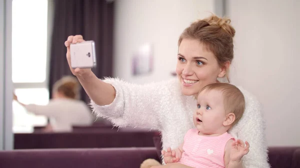 Selfie anne ve kızı evde. Çocuklu güzel bir kadın telefonuyla fotoğraf çekiyor. — Stok fotoğraf