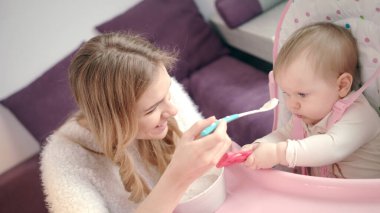 Bebek kaseden püre yiyor. Bebeği bebek mamasıyla besleyen kadın.