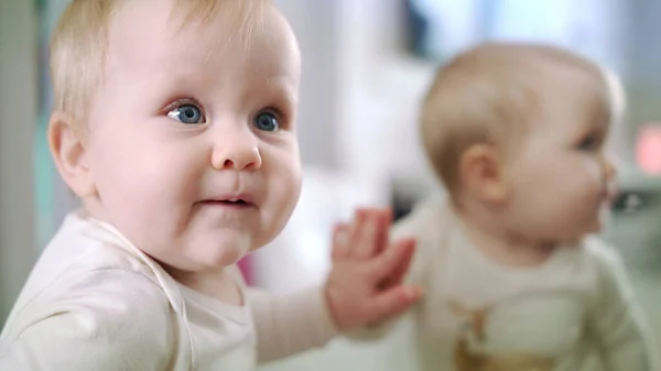 Bebé con ojos azules mirando a mamá y mordiéndose el dedo. Linda niña —  Fotos de Stock