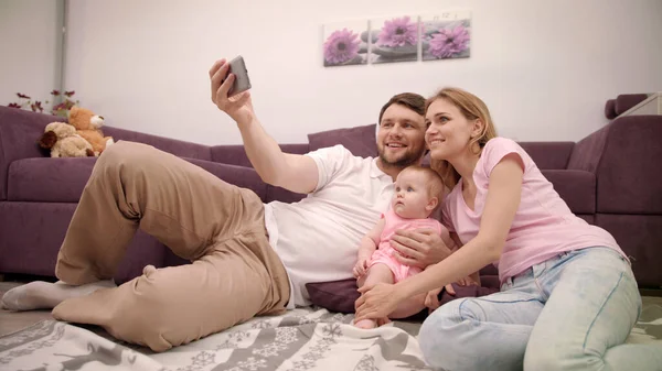 Una familia feliz haciendo selfies en casa. Padre tomar fotos con la esposa y la hija —  Fotos de Stock