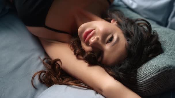 Muchacha atractiva acostada sobre almohadas suaves en la cama. Mujer seductora mirando cámara — Vídeos de Stock