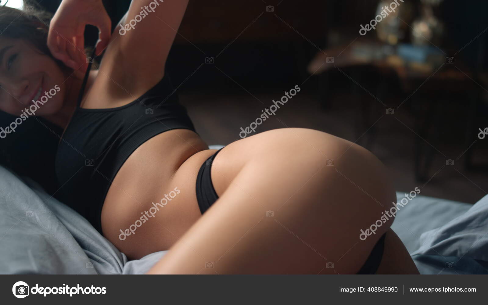 Perfecta chica del cuerpo sonriendo camara en el dormitorio. Mujer atractiva acostada en la cama del estomago. Foto de stock 408849990 stockbusters