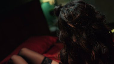 Genç esmer, kırmızı ipek çarşafların üzerine düşüyor. Seksi kadın başını tekrar yatağa atıyor..