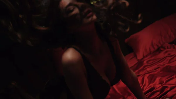 Saten çarşafların üzerinde diz çökmüş muhteşem bir kadın. Çekici kız seksi iç çamaşırlarıyla poz veriyor.