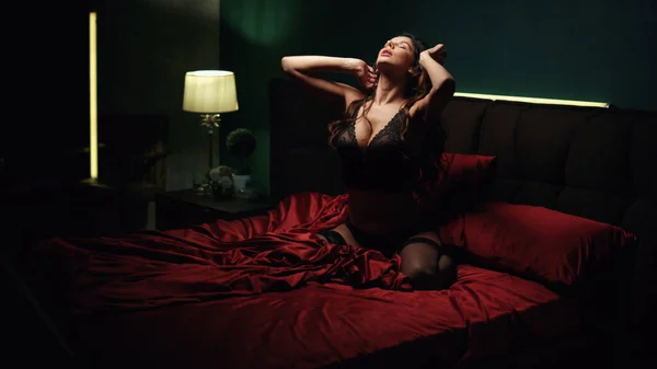 Пристрасна жінка торкається шовкового ліжка. Сексуальна дівчина білизна позує в спальні . — стокове фото