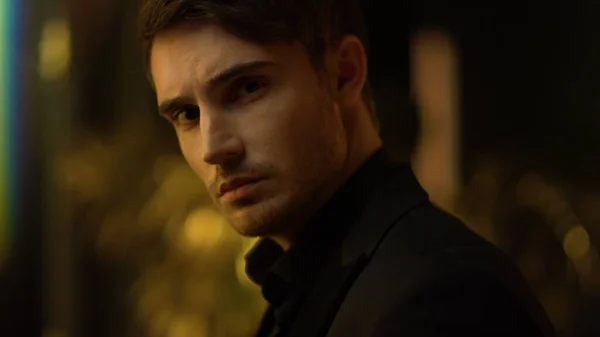 Karanlık arka planda düşünen şehvetli bir adam. Kapalı alanda yüzüne dokunan odaklanmış bir adam..