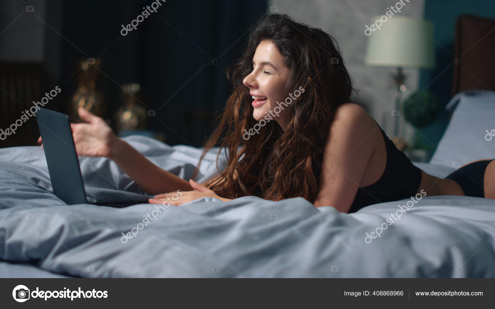 Smiling girl having video chat laptop in bed. Sexy woman using computer bedroom Stock Photo stockbusters 408868966