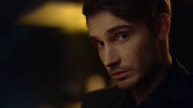 İçerideki kameraya odaklanmış adam. Yakışıklı adam, önünde oturan birini inceliyor.