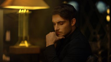 Odaklanmış üst düzey yönetici içeride sandalyede kafa yoruyor. Ciddi bir adam çeneye dokunuyor..