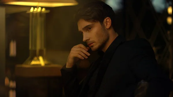 Zeki adam karanlık arka planda düşünceler içinde. Zengin adam koltukta oturuyor.