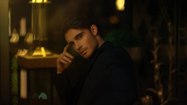 Karanlık odada oturan dalgın patron. Bulanık arkaplanda yüzüne dokunan genç adam.