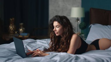 Bilgisayar odasında daktilo eden mükemmel bir vücut kızı. Kendine güvenen bir kadın dizüstü bilgisayarla yatakta yatıyor.