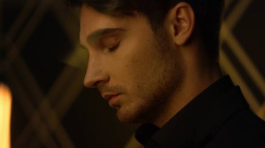 Güzel bir adamın arka planı bulanıklaşıyor. Genç adam içeride kameraya bakıyor..