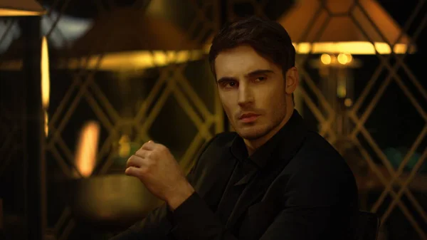 Siyah takım elbiseli üst yönetici içeride sandalyede oturuyor. Ciddi adam yana bakıyor..